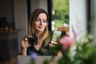 Frau sitzt beim Kaffee mit Smartphone in der Hand